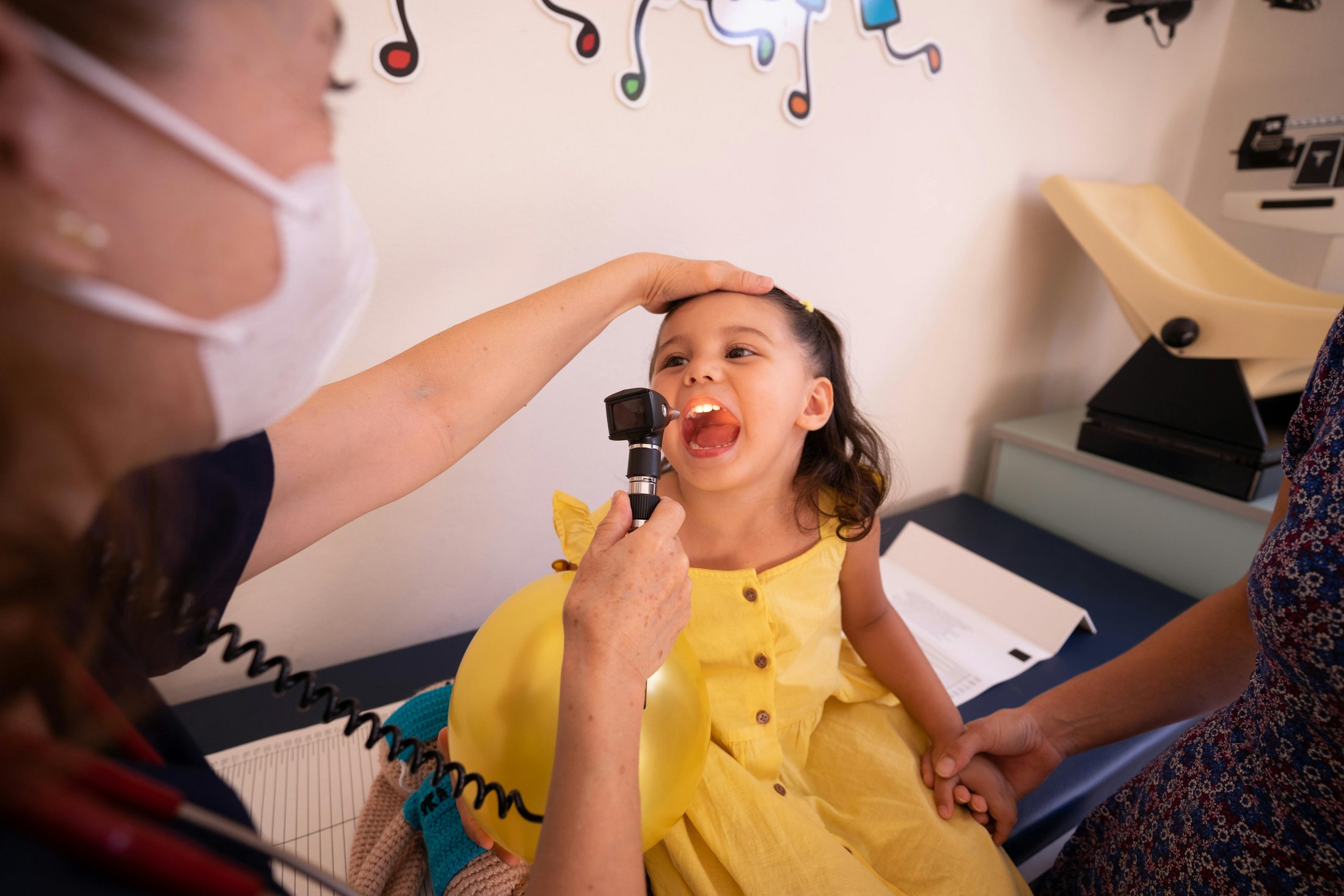 A doctor examining a little girl’s mouth during a health check-up.