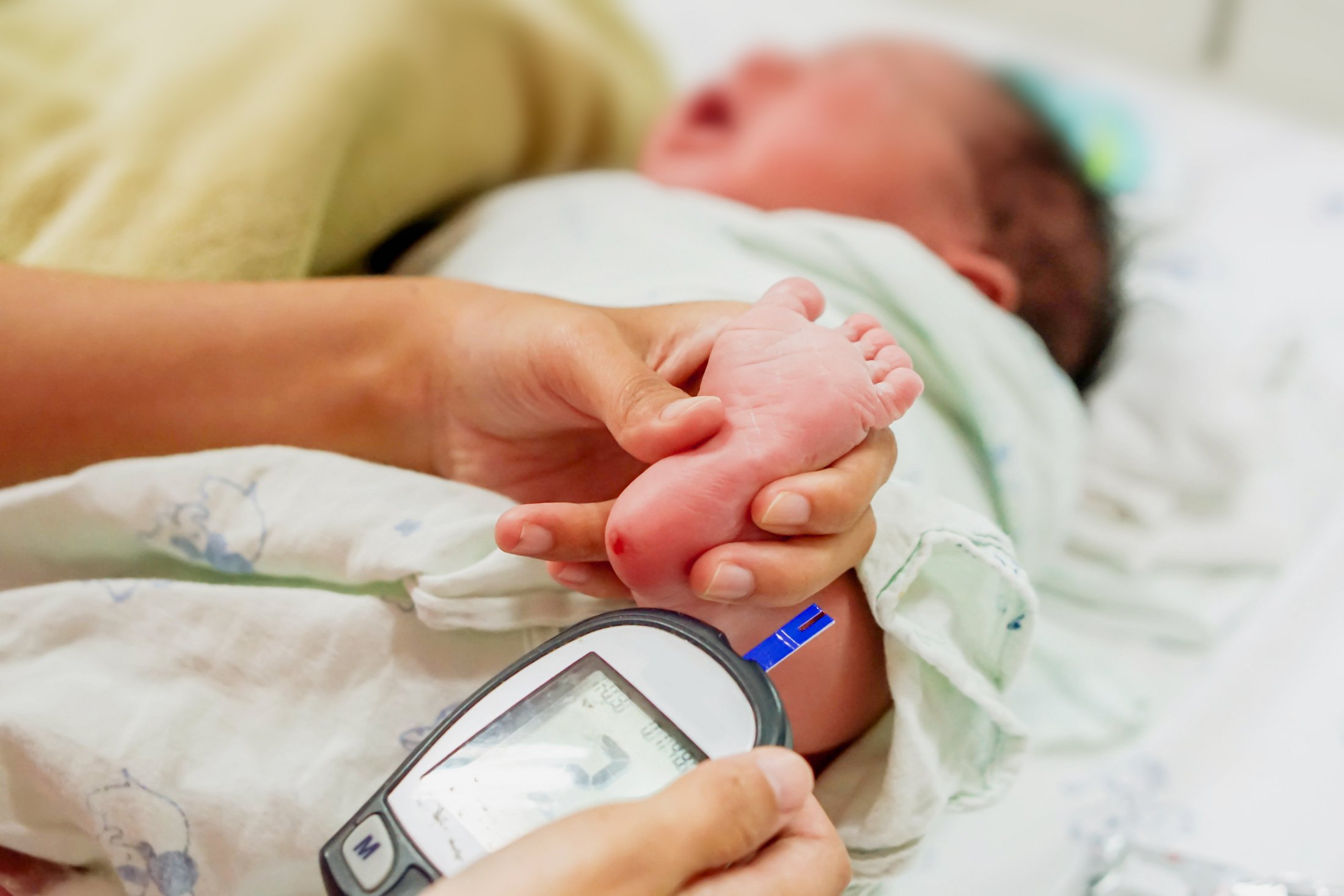 Close-up of a newborn’s foot being tested for blood sugar.