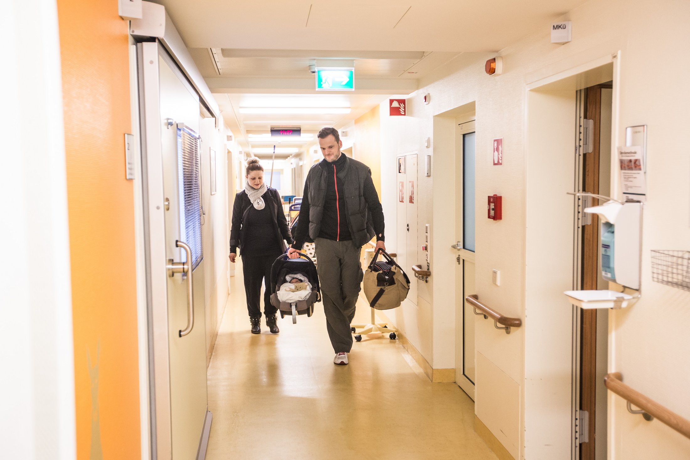 Parents carrying their baby out of hospital after neonatal care.