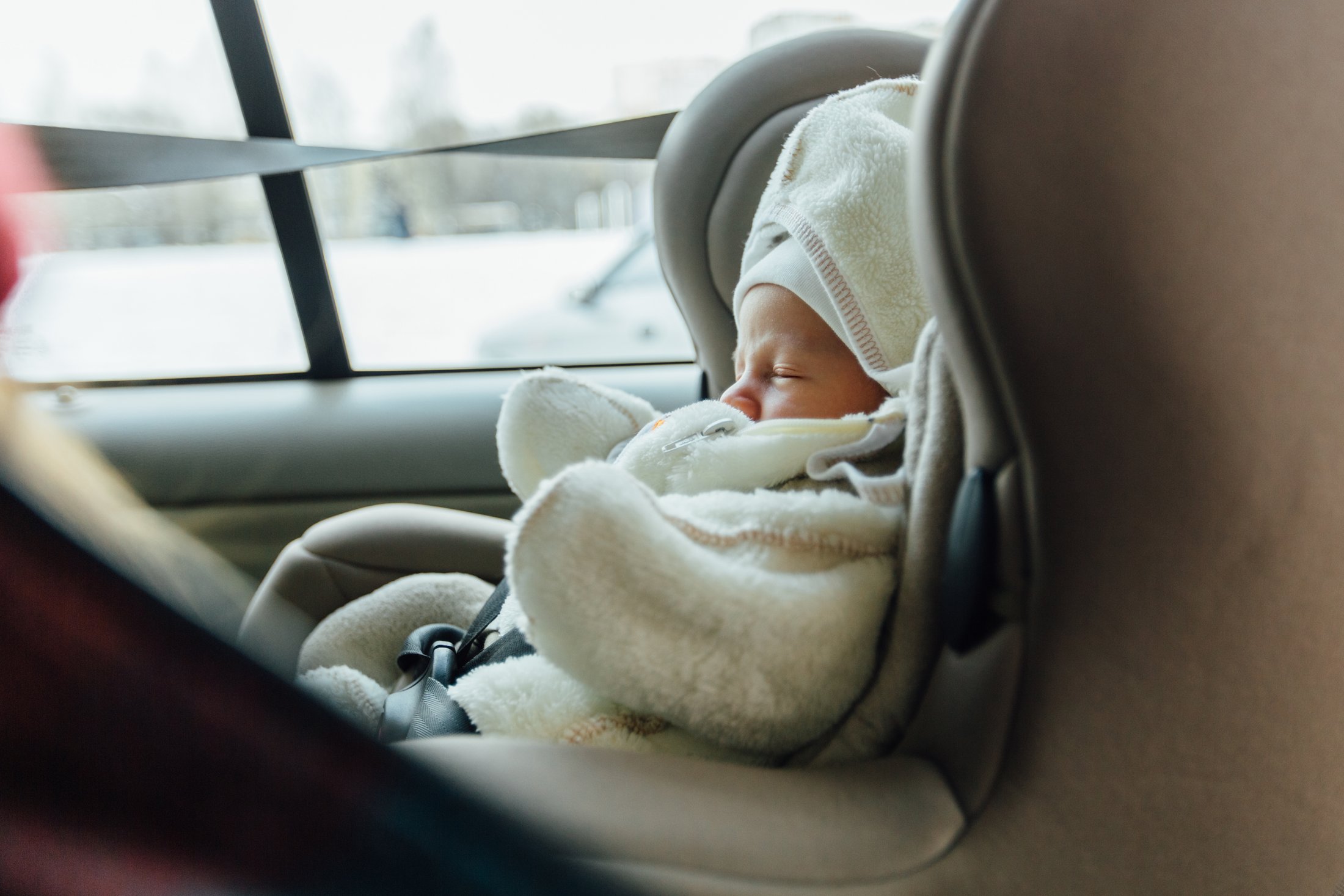 Premature baby sleeping safely in a car seat during a journey home from hospital.