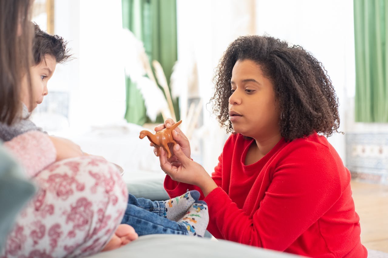 Woman showing toy to an attentive child.