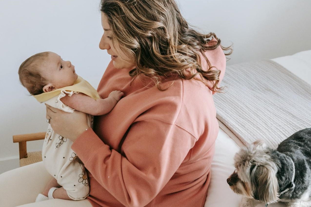 Mother holding her baby while seated on a chair.