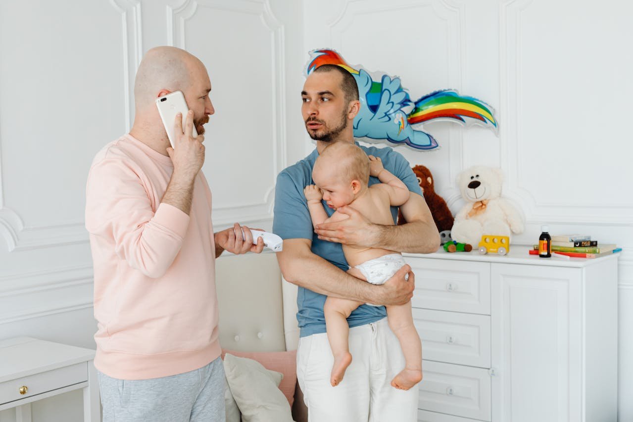 Two dads caring for their baby in a nursery.