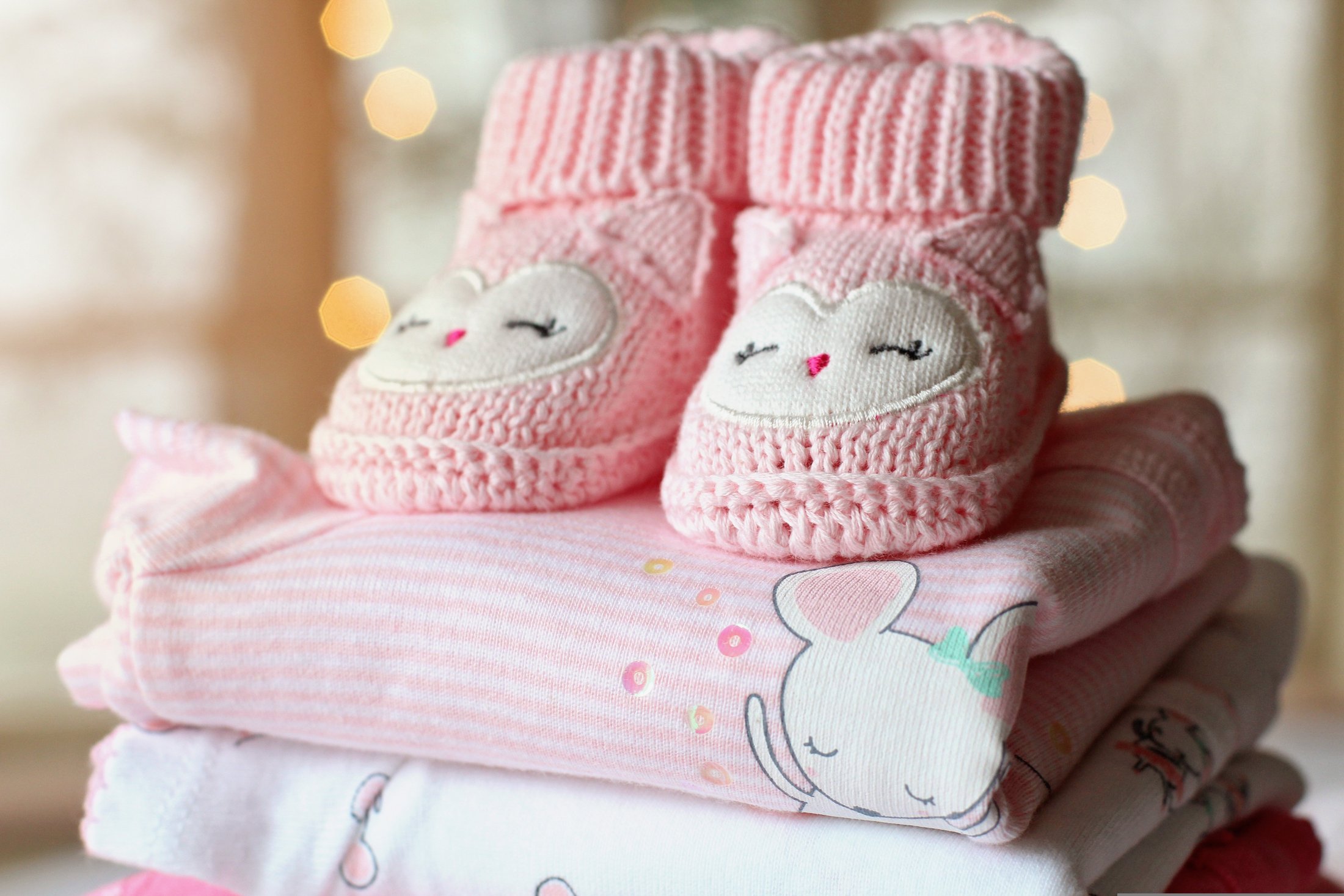 Close-up of pink baby booties on folded baby clothes.