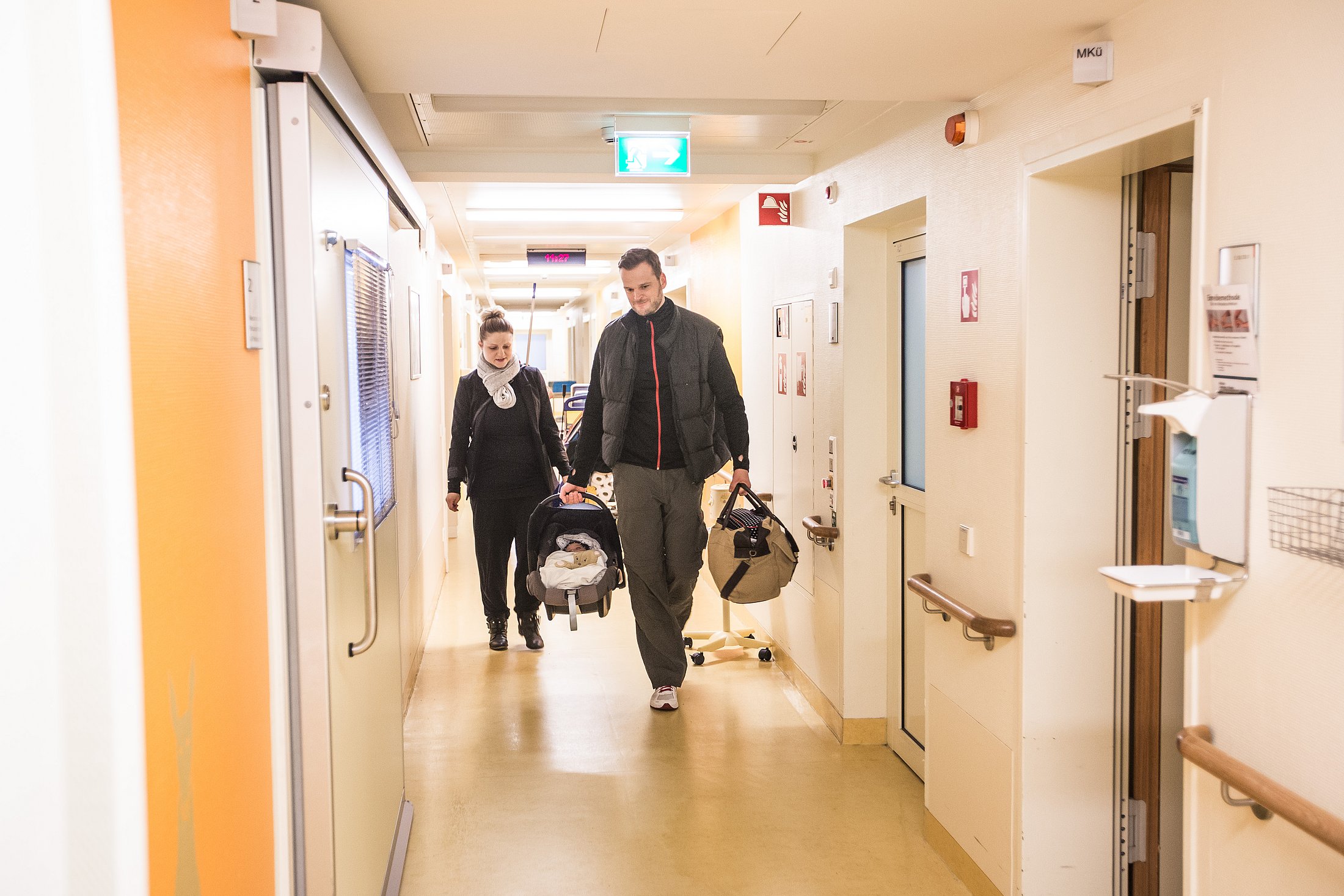 Parents carrying their baby out of hospital after neonatal care.