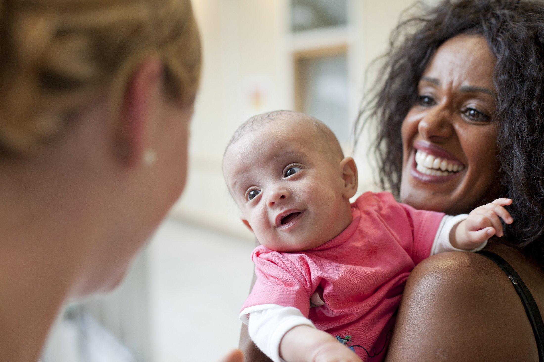 Mother smiling while holding her happy baby born prematurely.