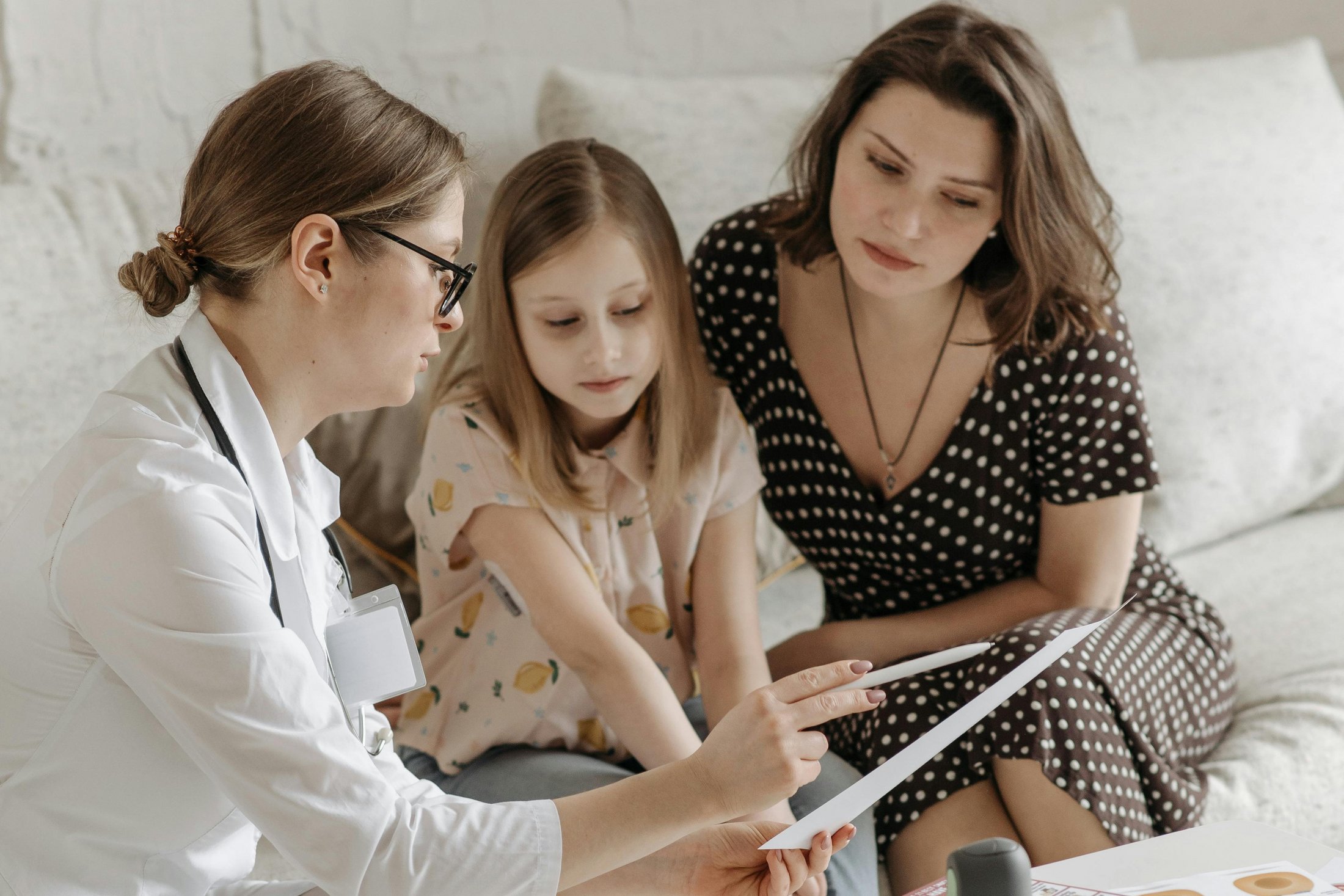 A doctor consulting with a mother and daughter at home.