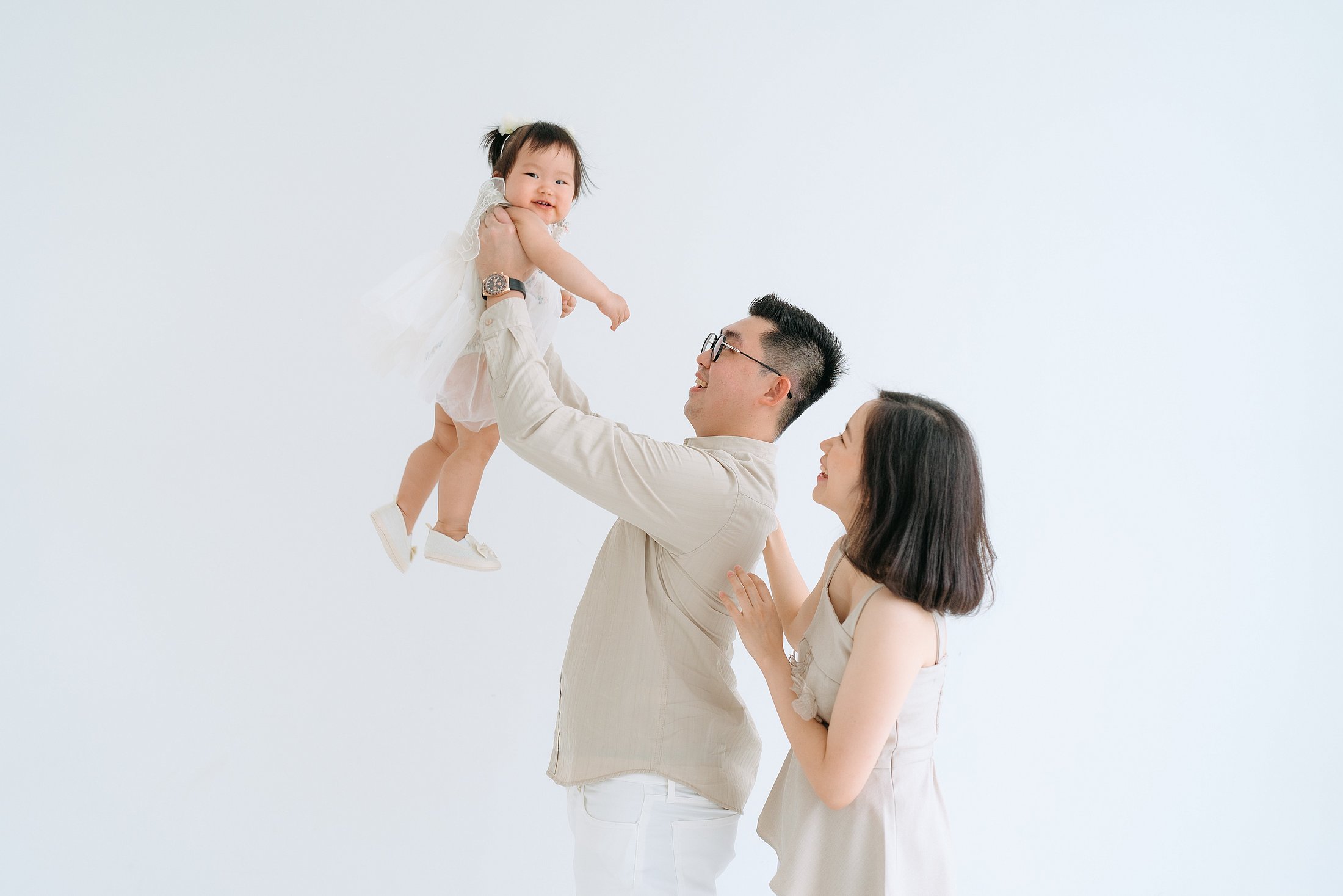 Parents lifting their baby in the air, sharing a joyful moment.