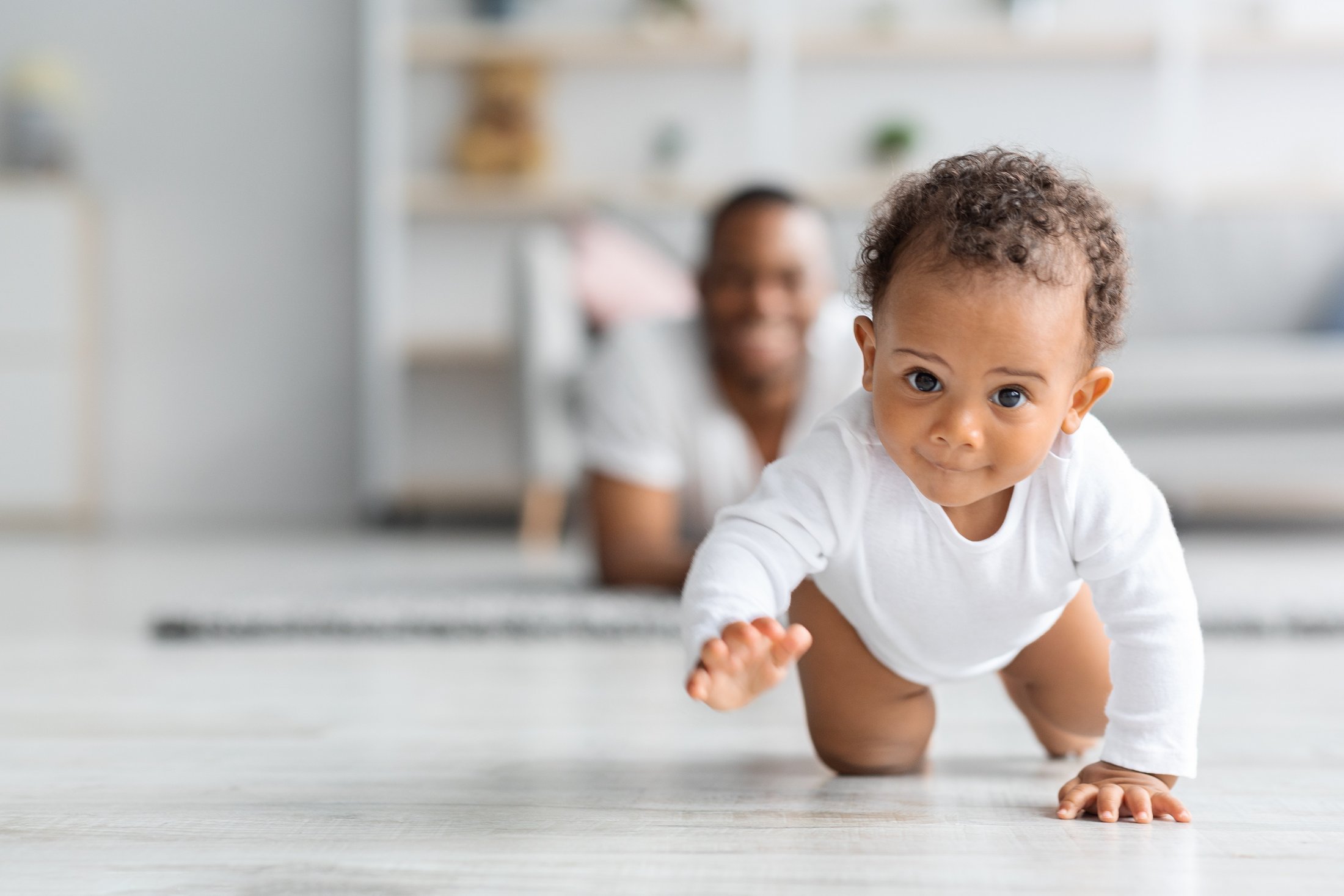 A baby happily crawling on the floor, showing developmental progress.