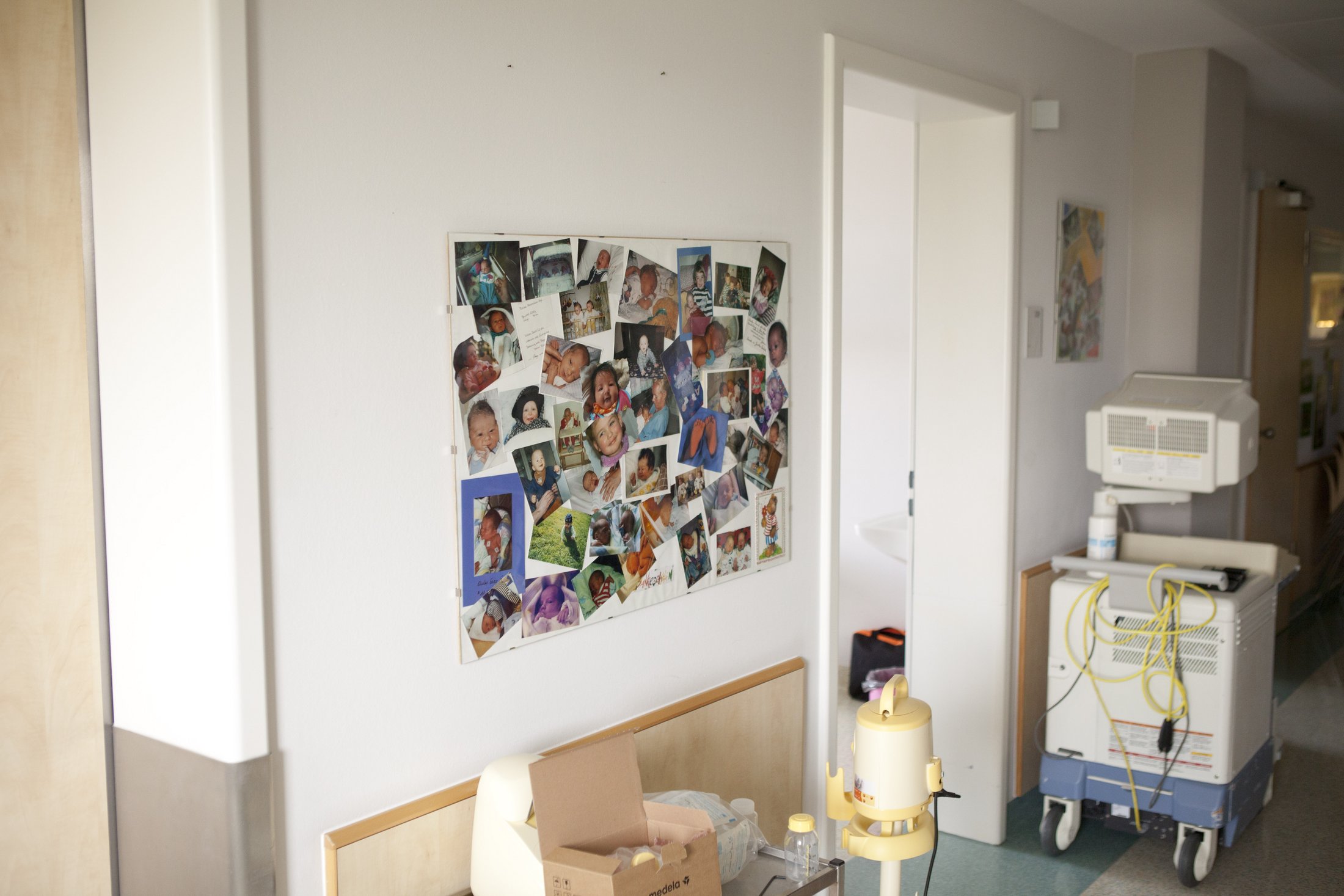 A collage of baby photos on a hospital wall.