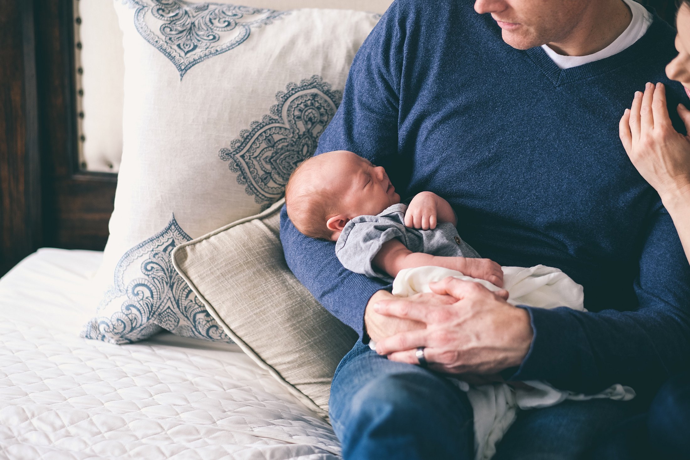 A newborn baby sleeping in their father’s arms.