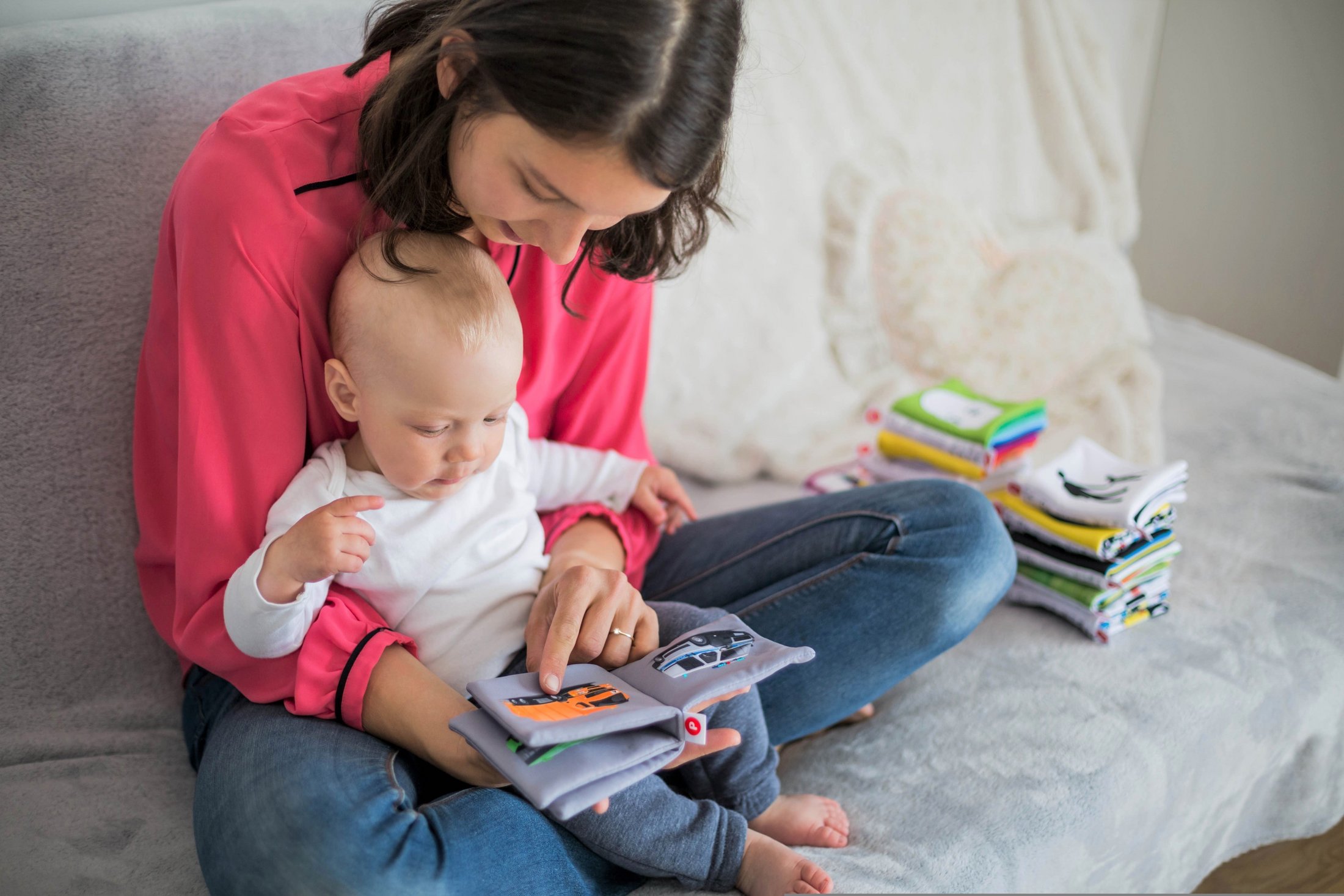 Mother reading a book to her baby while sitting on a sofa.