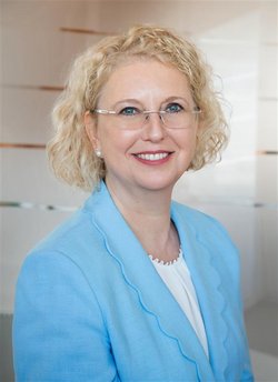A professional headshot of Silke Mader, wearing glasses and a light pink blazer.