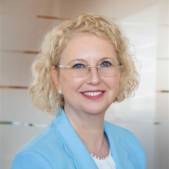 A professional headshot of Silke Mader, wearing glasses and a light pink blazer.