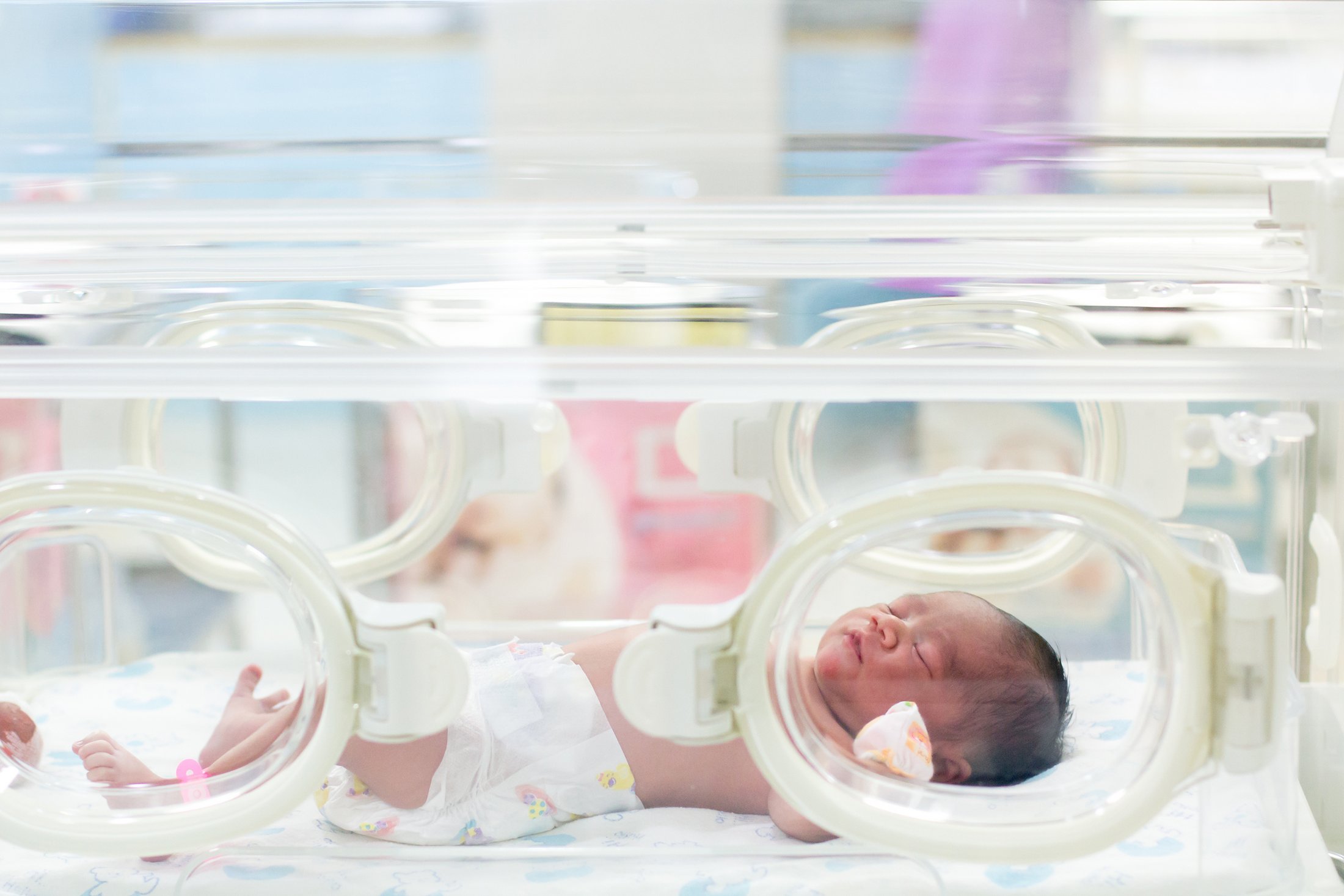 Premature newborn resting in a hospital incubator.