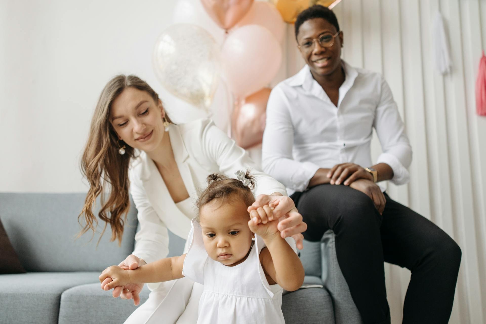 Parents helping their toddler walk while celebrating progress.