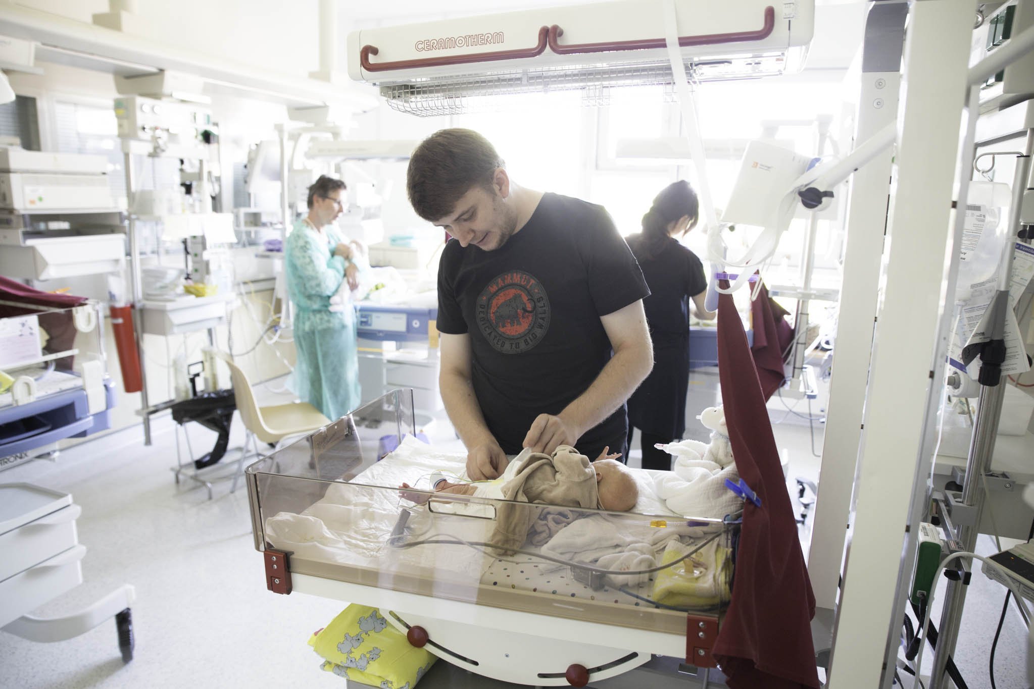 Father tending to a premature baby in hospital.