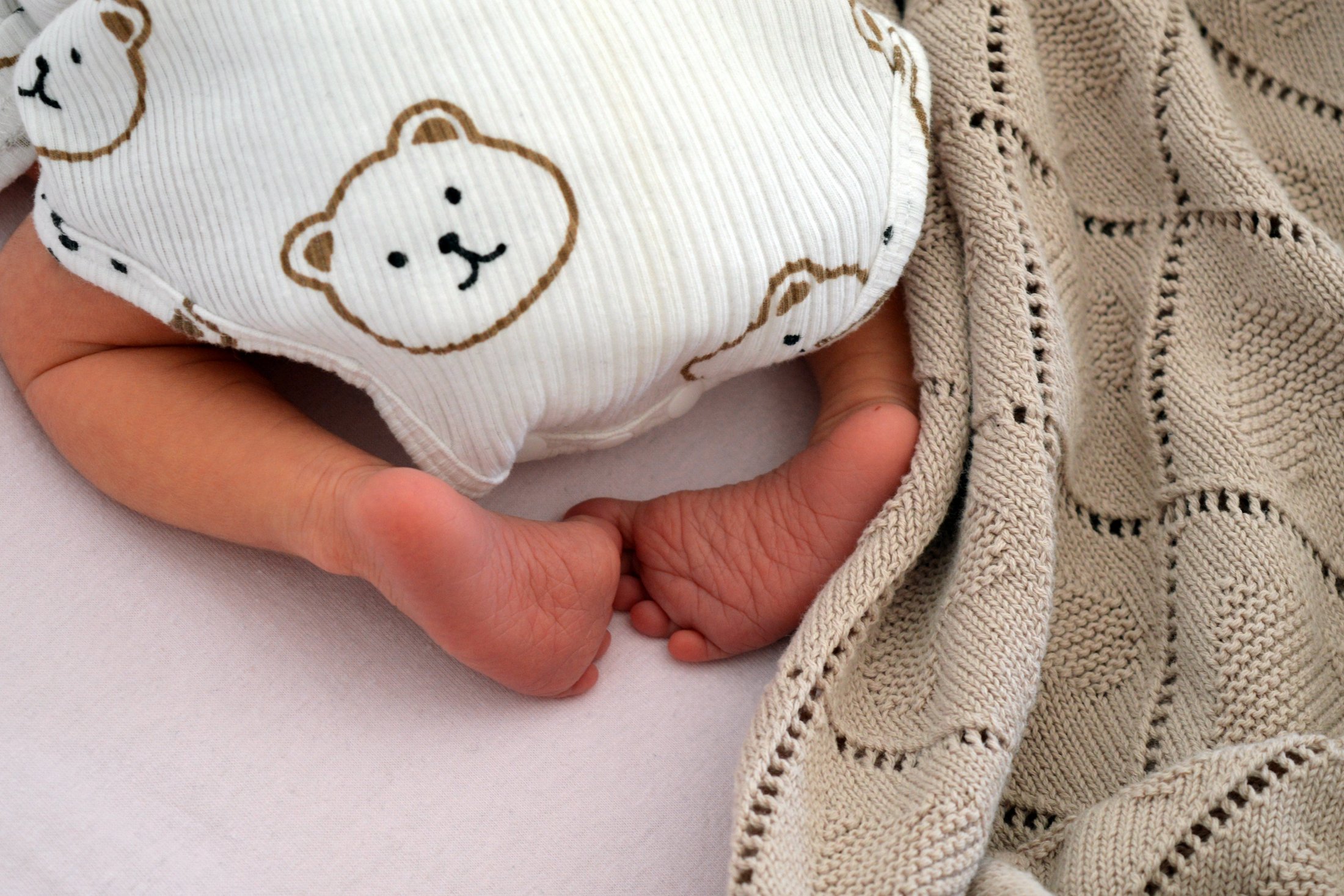 Close-up of premature baby’s feet covered with a blanket.