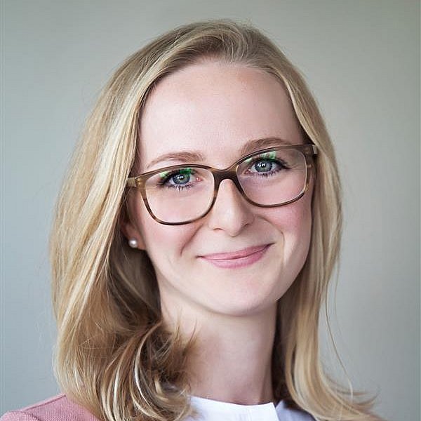 Portrait of Aurelia Abenstein with glasses and light background.