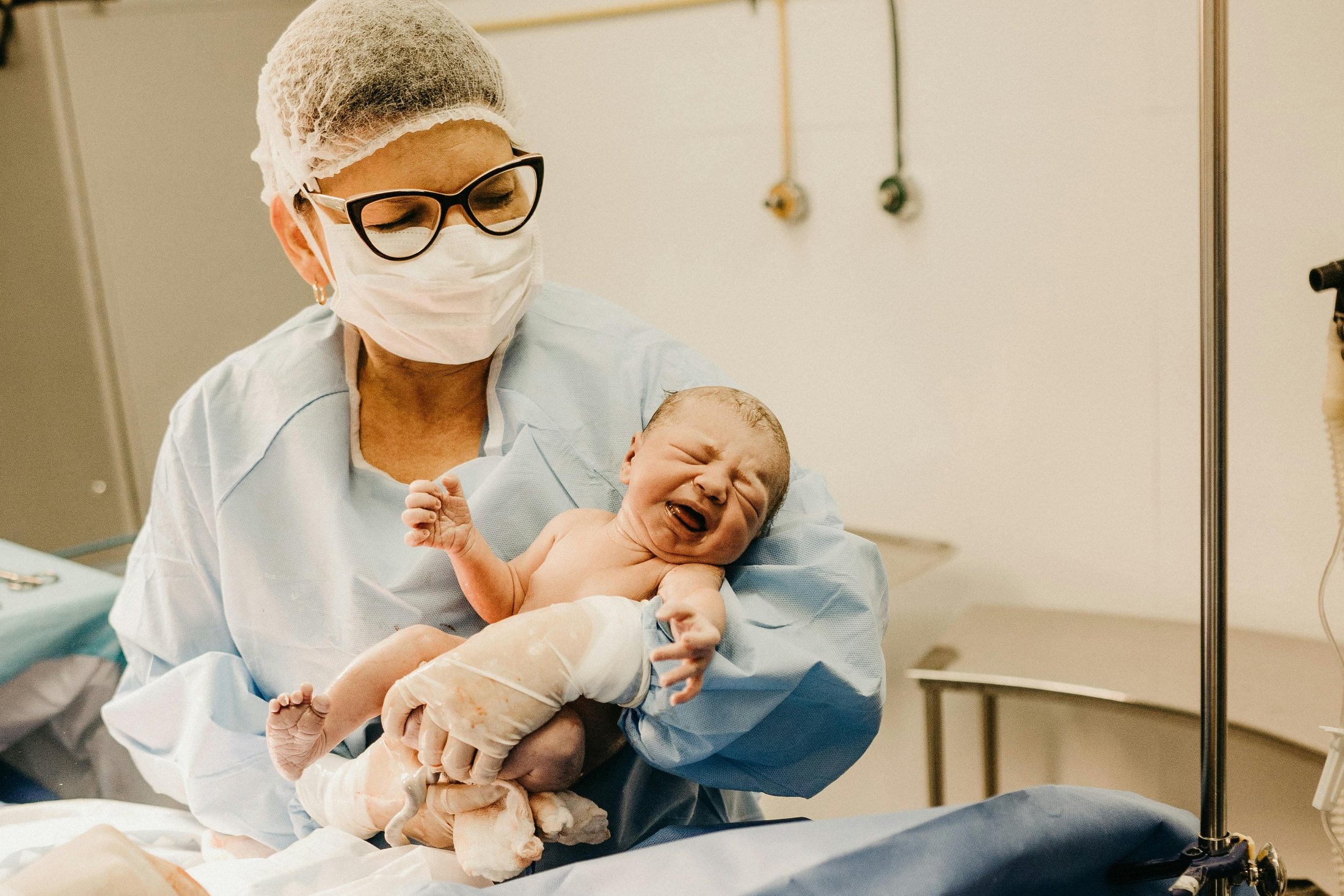 Doctor holding a crying newborn baby in the delivery room.