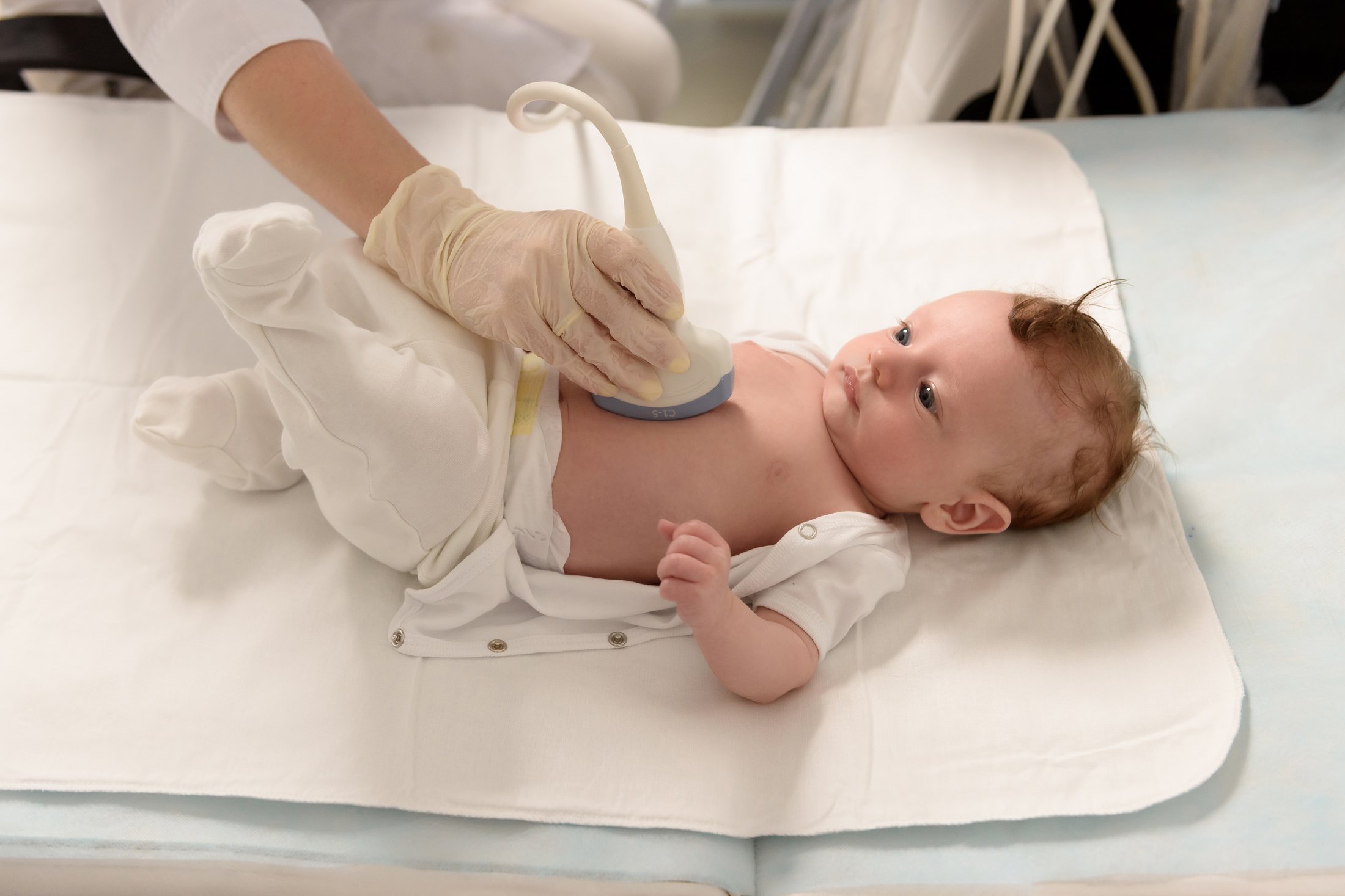 A medical professional performing an ultrasound on a baby.