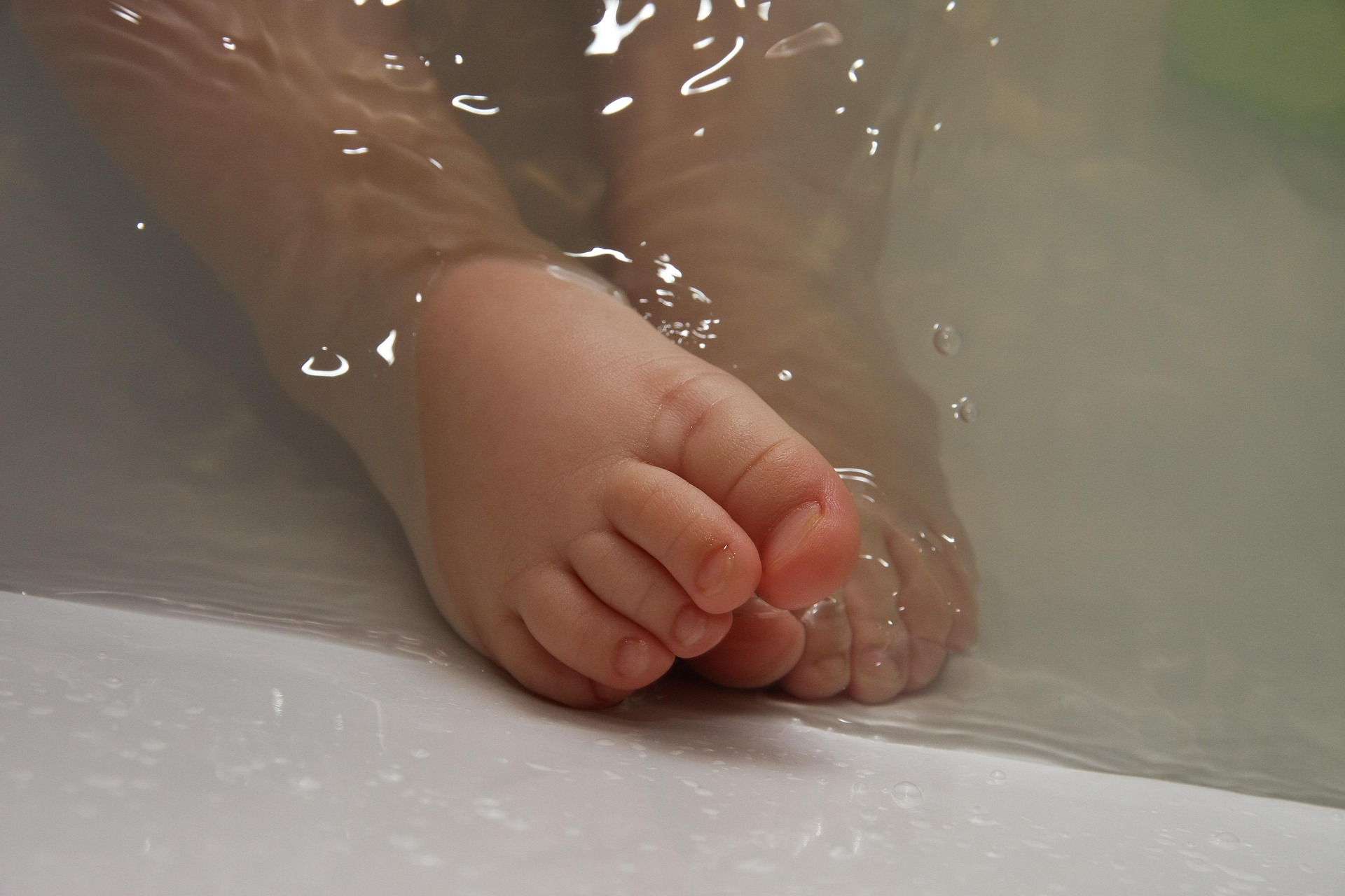 Close-up of a baby’s feet in water during a gentle bath.