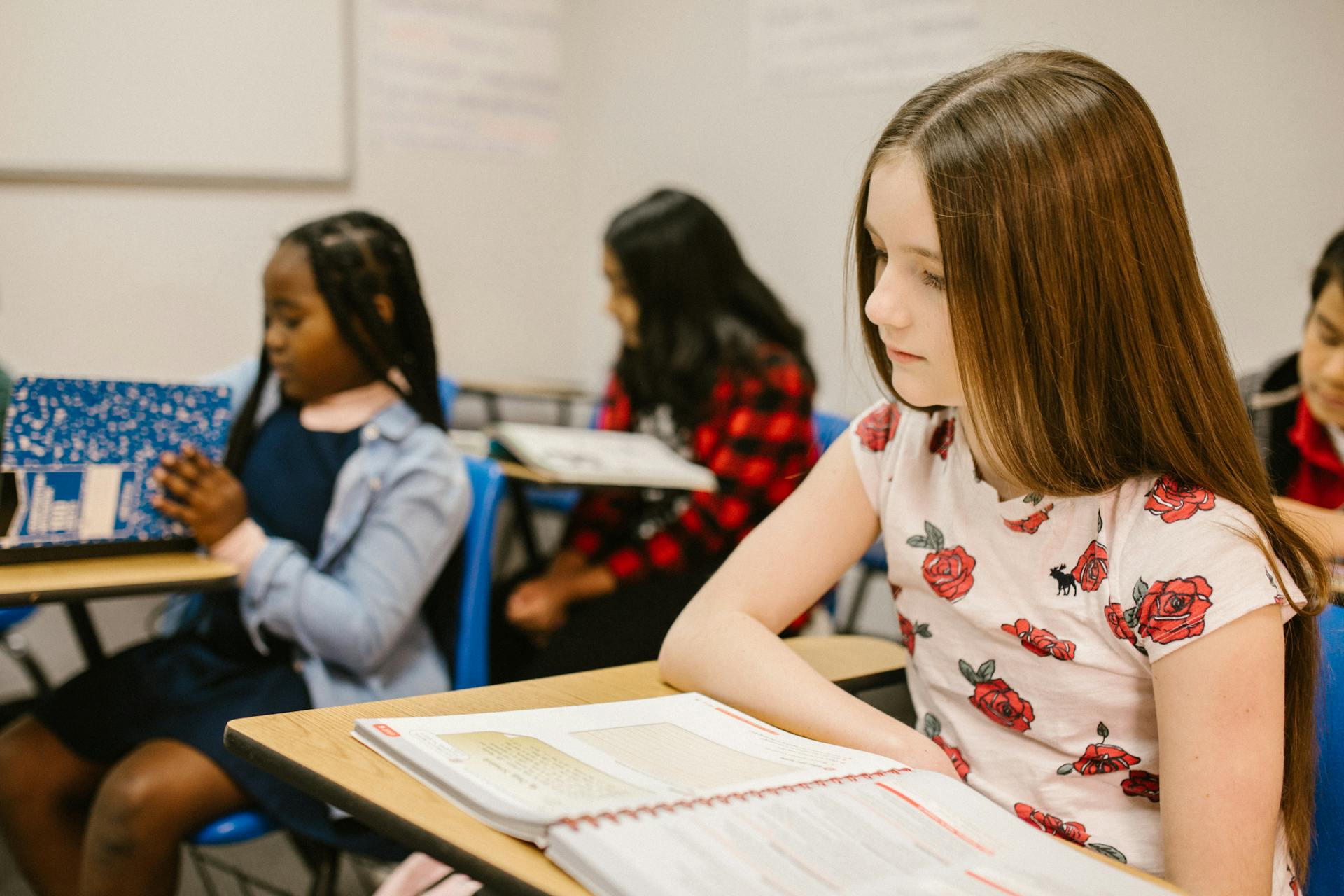 A girl paying attention in class, with classmates in the background.